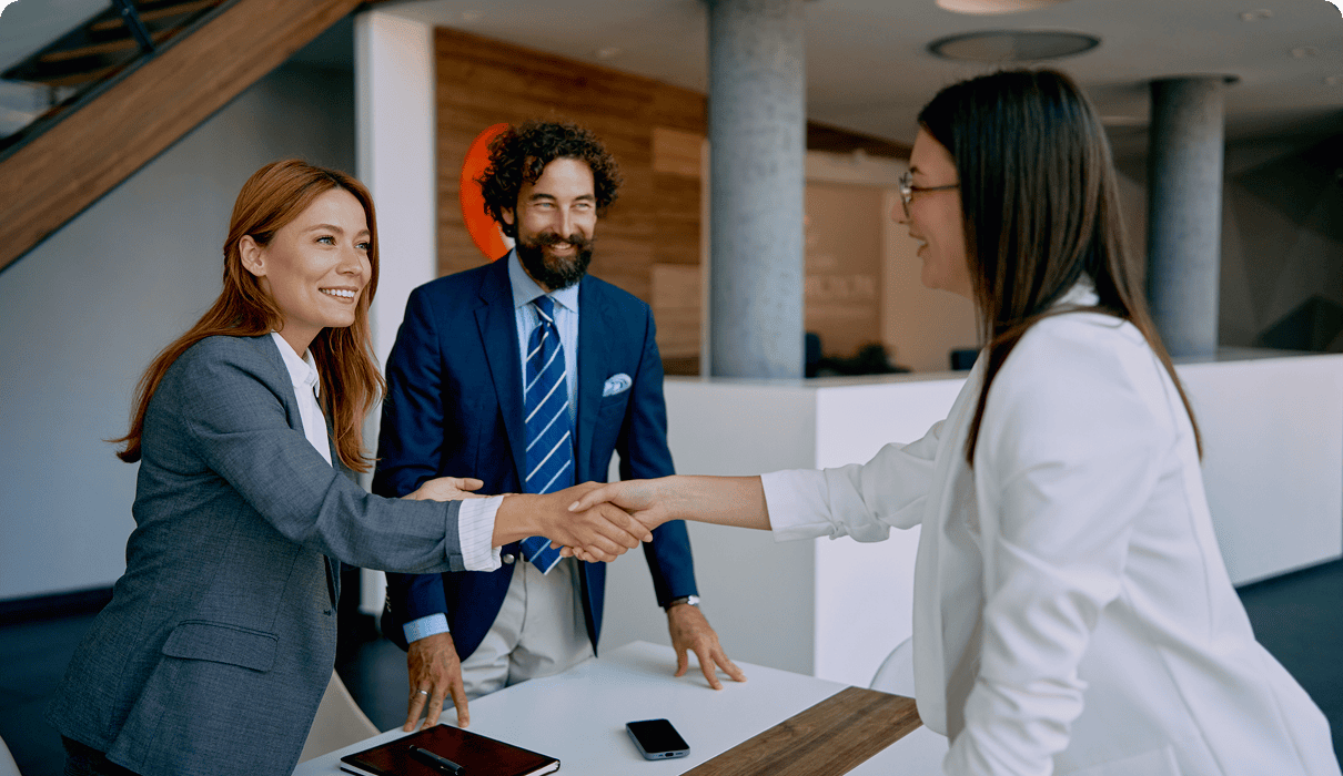 Three professionals shaking hands at meeting.